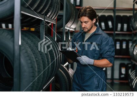 Notepad in hands. Man is in the tire fitting car service 133219573