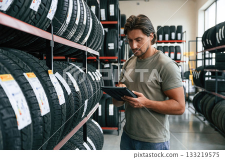 Notepad in hands. Man is in the tire fitting car service 133219575
