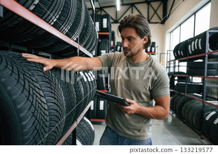 Quality control, manager is looking for stuff. Man is in the tire fitting car service Quality control, manager is looking for stuff. Man is in the tire fitting car service 133219577