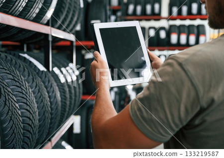 Copy space on the digital tablet. Man is in the tire fitting car service Copy space on the digital tablet. Man is in the tire fitting car service 133219587