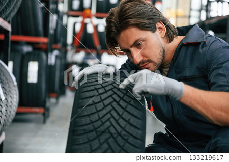 Warehouse with many tires. Man is in the tire fitting car service 133219617
