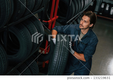 Taking one tire to for changing. Man is in the tire fitting car service Taking one tire to for changing. Man is in the tire fitting car service 133219631