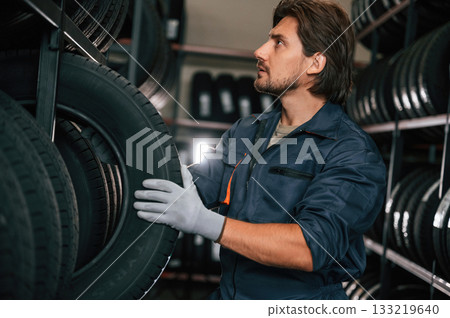 In the warehouse. Man is in the tire fitting car service 133219640