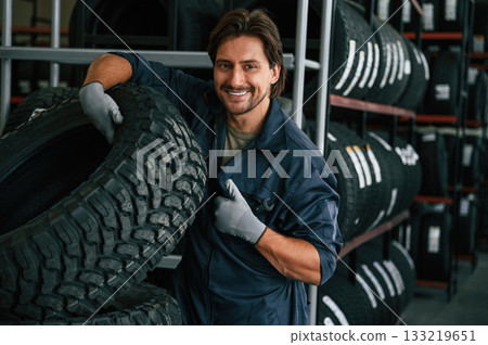 Professional worker is with wheel. Man is in the tire fitting car service Professional worker is with wheel. Man is in the tire fitting car service 133219651