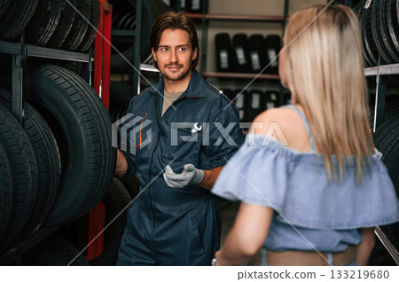 Giving the advice. Woman is in the tire fitting auto shop with worker 133219680
