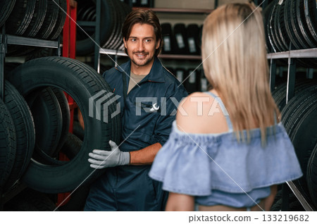 Giving the advice. Woman is in the tire fitting auto shop with worker Giving the advice. Woman is in the tire fitting auto shop with worker 133219682