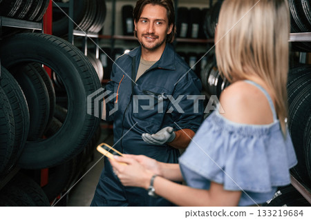 Woman is in the tire fitting auto shop with worker 133219684