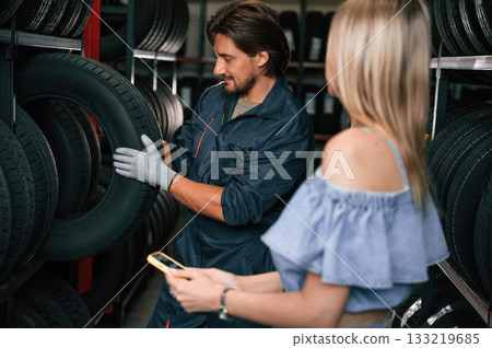Woman is in the tire fitting auto shop with worker Woman is in the tire fitting auto shop with worker 133219685