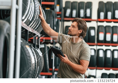 Digital tablet in hands. Man is in the tire fitting car service Digital tablet in hands. Man is in the tire fitting car service 133219724