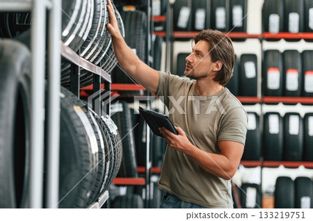 Digital tablet in hands. Man is in the tire fitting car service Digital tablet in hands. Man is in the tire fitting car service 133219751