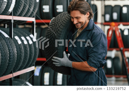 Cheerful, smiling. Man is in the tire fitting car service Cheerful, smiling. Man is in the tire fitting car service 133219752