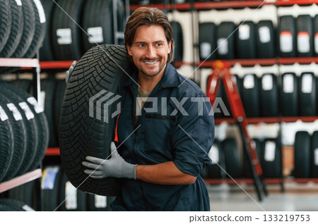 Cheerful, smiling. Man is in the tire fitting car service Cheerful, smiling. Man is in the tire fitting car service 133219753