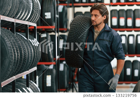Moving the tire. Man is in the tire fitting car service Moving the tire. Man is in the tire fitting car service 133219756