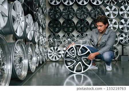 Big choice. Man is in the tire fitting car service 133219763