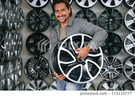 Big choice. Man is in the tire fitting car service 133219777