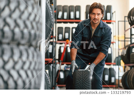 Front view, new wheel. Man is in the tire fitting car service 133219793