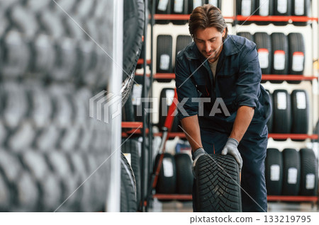 Front view, new wheel. Man is in the tire fitting car service Front view, new wheel. Man is in the tire fitting car service 133219795