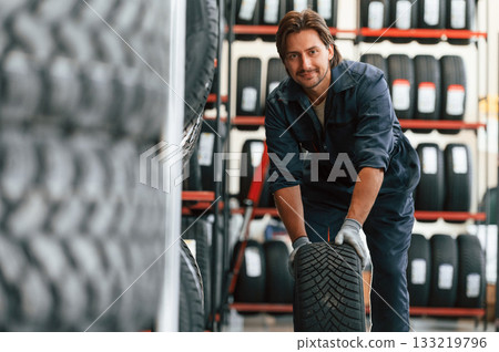 Front view, new wheel. Man is in the tire fitting car service Front view, new wheel. Man is in the tire fitting car service 133219796