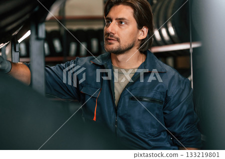 In professional uniform. Man is in the tire fitting car service 133219801