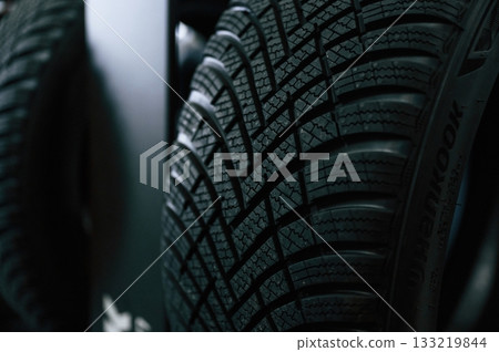 Particle close up view. New tires are placed on the storage rack in the car workshop Particle close up view. New tires are placed on the storage rack in the car workshop 133219844