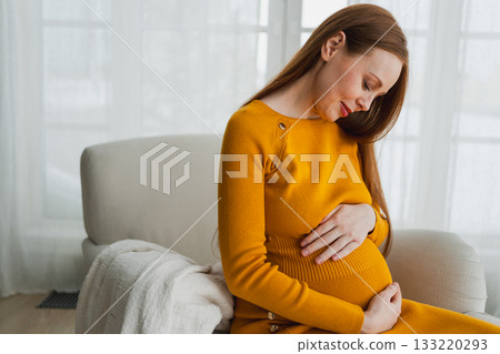 Pregnancy motherhood people expectation future. Pregnant woman with big belly sitting on chair near window at home. Girl hugging her tummy enjoying pregnancy. Maternity tenderness parenthood new life Pregnancy motherhood people expectation future. Pregnant woman with big belly sitting on chair near window at home. Girl hugging her tummy enjoying pregnancy. Maternity tenderness parenthood new life 133220293