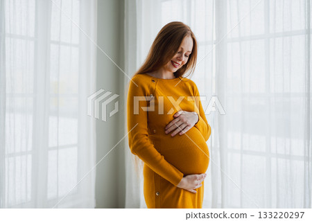 Pregnancy motherhood people expectation future. Pregnant woman with big belly standing near window at home. Girl hugging her tummy enjoying pregnancy. Maternity tenderness parenthood new life concept Pregnancy motherhood people expectation future. Pregnant woman with big belly standing near window at home. Girl hugging her tummy enjoying pregnancy. Maternity tenderness parenthood new life concept 133220297