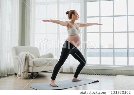 Pregnancy yoga fitness workout training. Pregnant woman practicing yoga at home. Pregnant girl doing sports exercise on yoga mat indoor. Woman with big belly have fitness training practicing asana 133220302