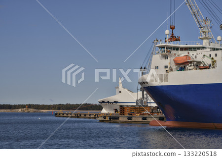 cargo ship moored at harbor pier with cranes, calm water, clear blue sky, port warehouses, logistic stillness, morning light, 133220518