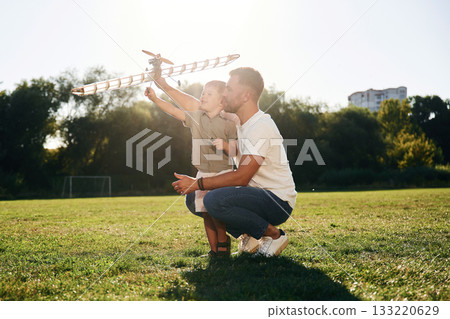 Father and son are on the field together with toy plane Father and son are on the field together with toy plane 133220629