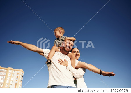 Mother and father are with son outdoors on the field 133220679