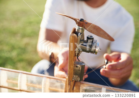 Made of wood. Man is on the field fixing the toy plane 133220891
