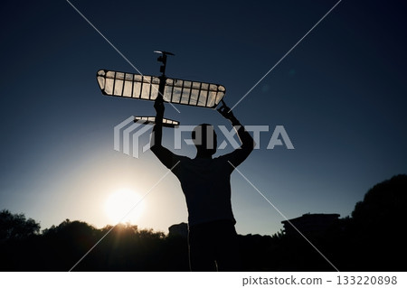 Man is holding wooden toy plane in hands, dark, dawn Man is holding wooden toy plane in hands, dark, dawn 133220898