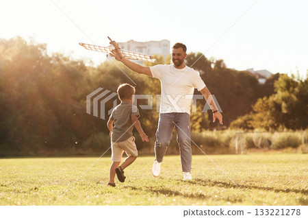 Running, fun. Father and son are on the field together with toy plane 133221278