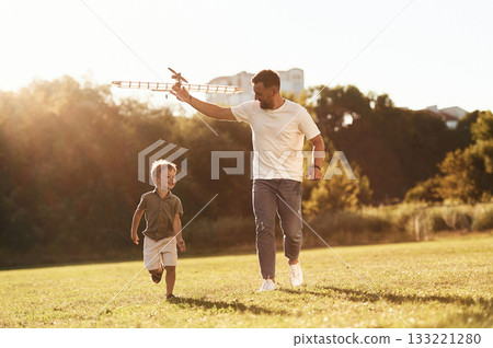 Running, fun. Father and son are on the field together with toy plane 133221280