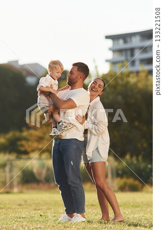 Parents and kid are happy. Mother and father are with son outdoors on the field 133221508