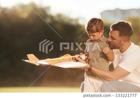 Broken, fixing it. Father and son are on the field together with toy plane 133221777