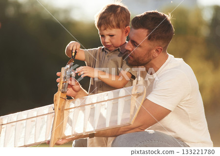 Broken, fixing it. Father and son are on the field together with toy plane 133221780