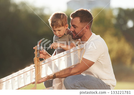 Broken, fixing it. Father and son are on the field together with toy plane Broken, fixing it. Father and son are on the field together with toy plane 133221781