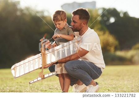 Broken, fixing it. Father and son are on the field together with toy plane Broken, fixing it. Father and son are on the field together with toy plane 133221782