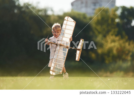 Cute little boy is playing with toy plane on the field Cute little boy is playing with toy plane on the field 133222045