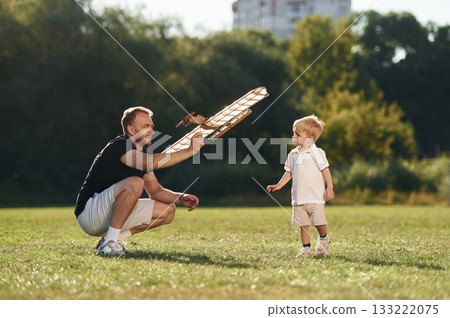 Father and son are on the field together with toy plane 133222075