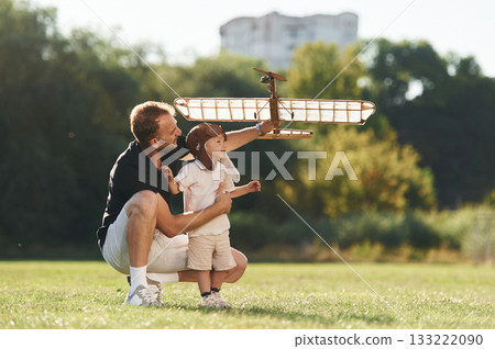 Having fun, sitting. Father and son are on the field together with toy plane Having fun, sitting. Father and son are on the field together with toy plane 133222090