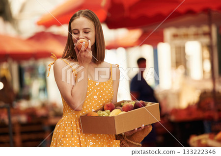 Box with peaches and grapes. Young woman is on the vegetable market or bazaar 133222346
