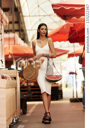 With baguette. Young woman is on the vegetable market or bazaar With baguette. Young woman is on the vegetable market or bazaar 133222367