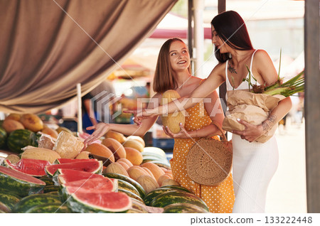They are looking for a watermelon. Two women are together on the marker or bazaar They are looking for a watermelon. Two women are together on the marker or bazaar 133222448