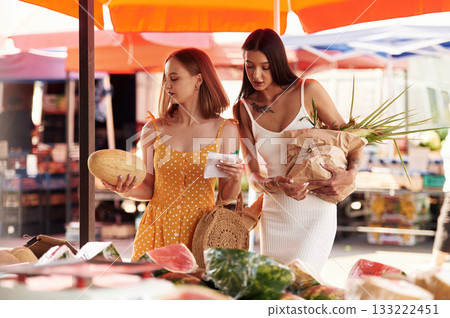 Holds a melon. Two women are together on the marker or bazaar Holds a melon. Two women are together on the marker or bazaar 133222451