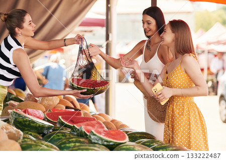 Buying fruits from the seller. Two women are together on the marker or bazaar Buying fruits from the seller. Two women are together on the marker or bazaar 133222487
