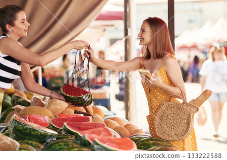Yellow dress, and with watermelon. Young woman is on the vegetable market or bazaar 133222588