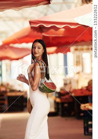 In white dress. Young woman is on the vegetable market or bazaar 133222612