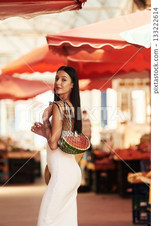 Just bought the watermelon. Young woman is on the vegetable market or bazaar 133222614